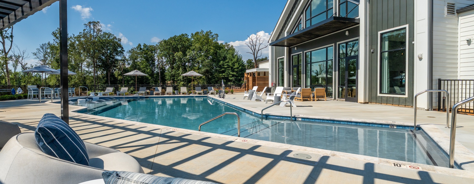 Pool side lounge chairs, exterior of clubhouse and outdoor showers