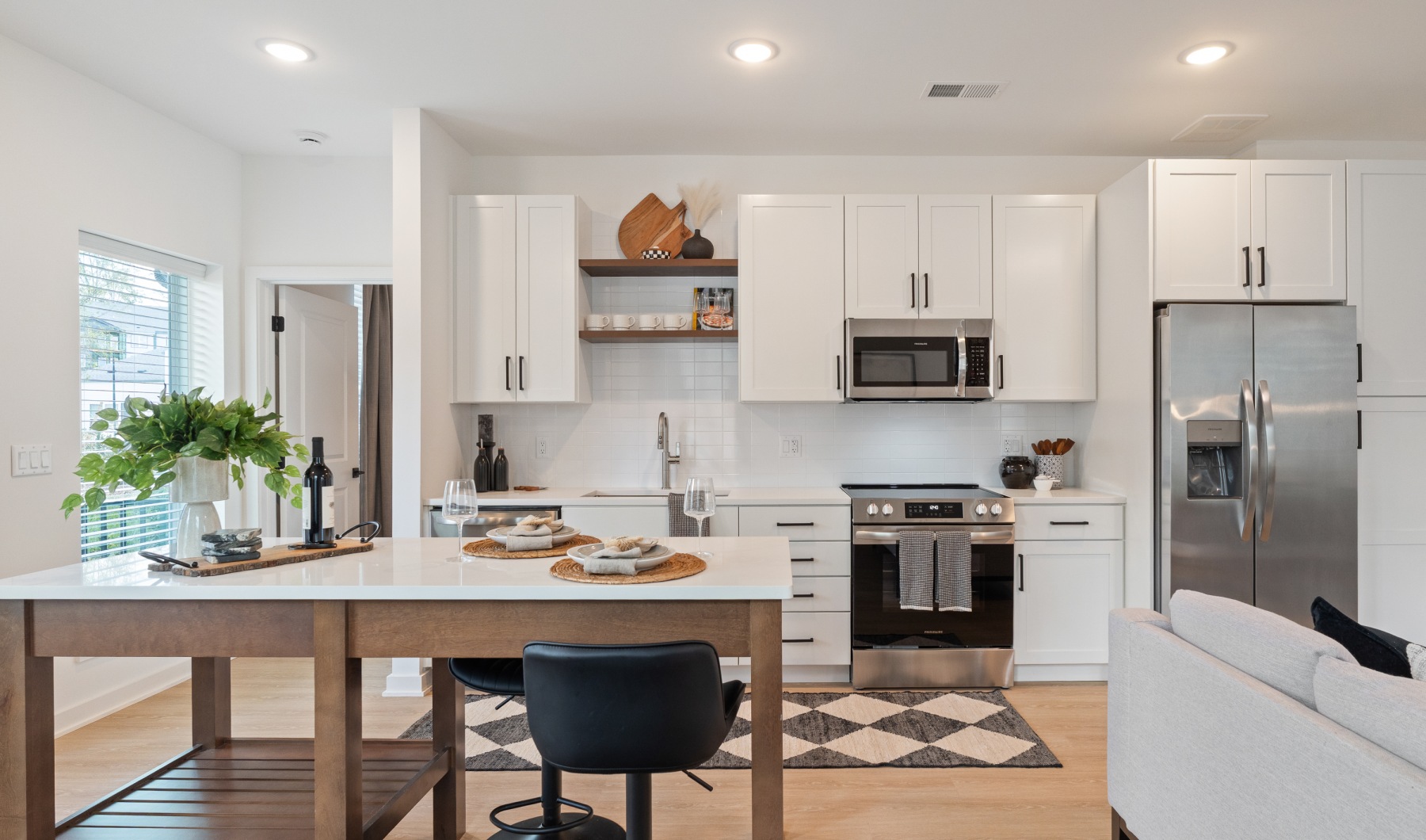 Open concept kitchen with eat in island, stainless steel appliances, and white cabinetry