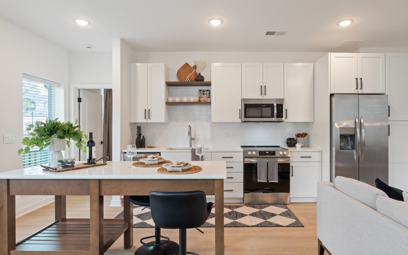 Open concept kitchen with eat in island, stainless steel appliances, and white cabinetry