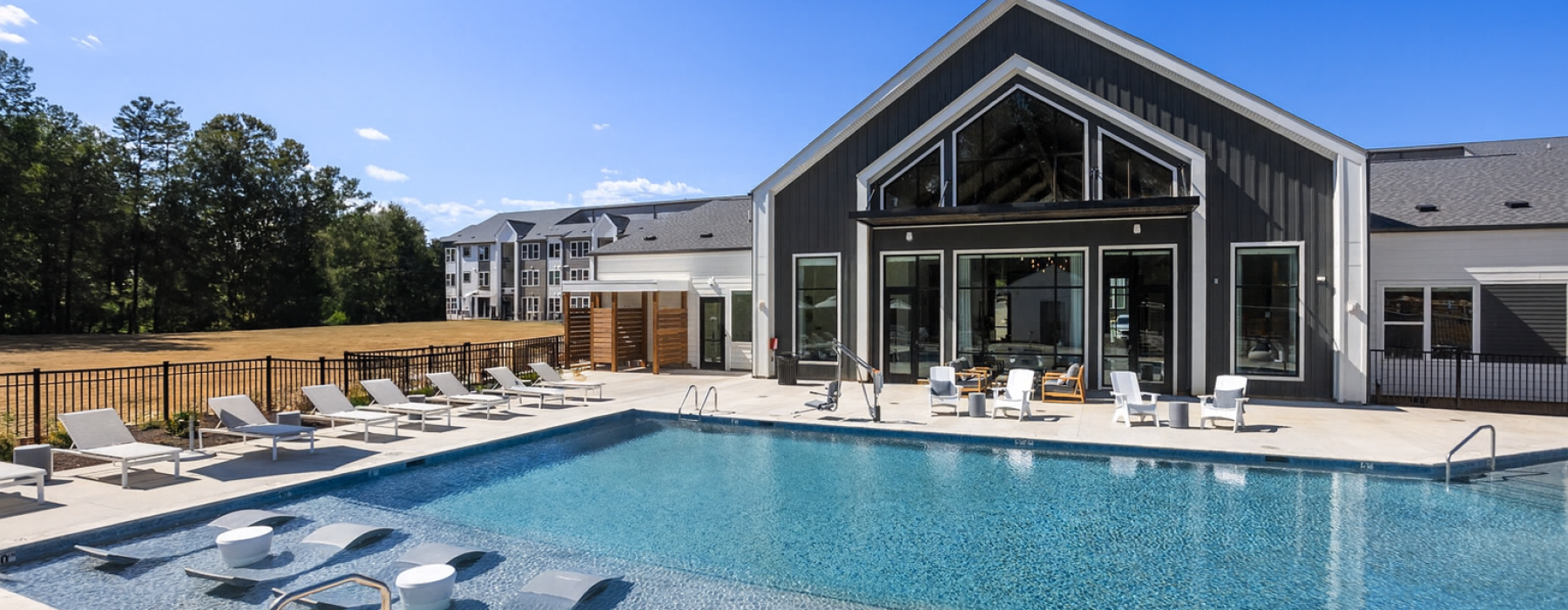 Pool side lounge chairs, exterior of clubhouse and outdoor showers